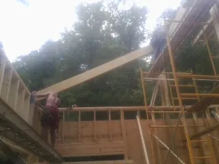 Carpenter raising a rafter beam on a new second story frame in Benson