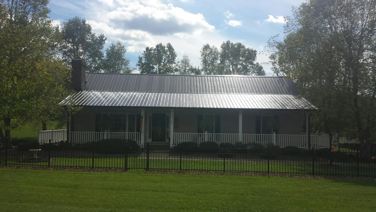 Gray metal roof on a brick ranch with a full width front porch — Gutter Guard Installation work by our crew in Benson